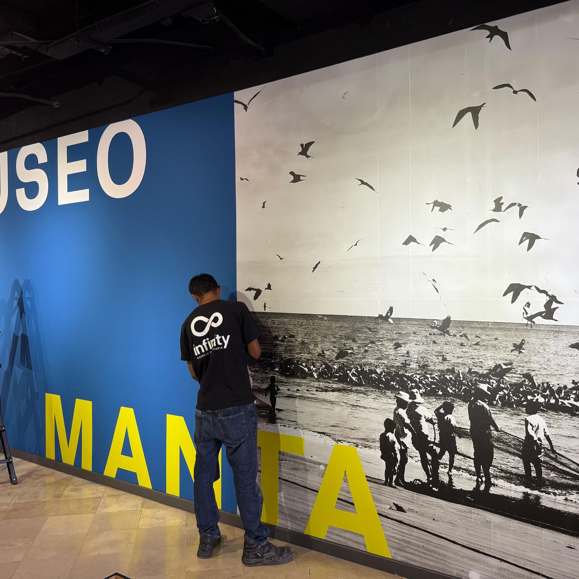 Técnico de Infinity instalando una gráfica mural en el museo